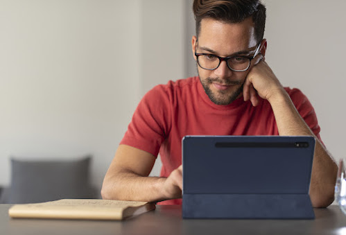 Homme en chemise rouge qui regarde une tablette