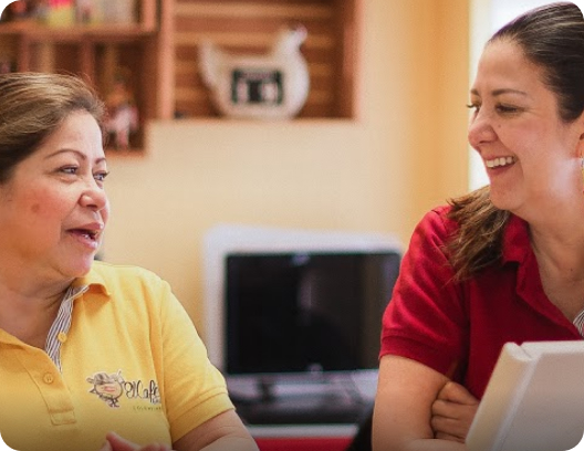 Two women are having a conversation. One is smiling while the other talks.