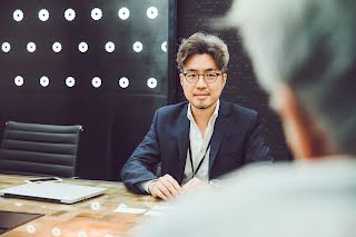 A man in a spects sitting on a chair.