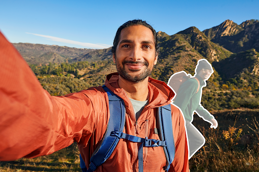 Ein junger Mann entfernt eine Person, die unbeabsichtigt durchs Bild gelaufen ist, aus dem Selfie, das er beim Wandern in den Bergen aufgenommen hat.