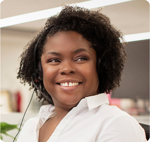 A woman wearing a telephone headset smiles as she looks at something past the camera.