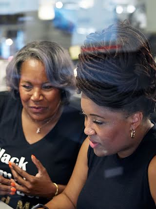 2 women, looking intensely at a computer.