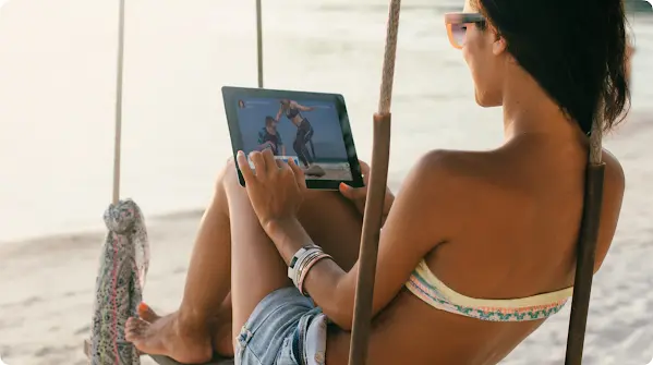 Mulher olhando para um tablet na praia