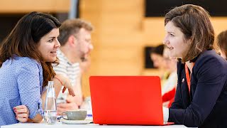 2 women sitting in front of each other, having a conversation.