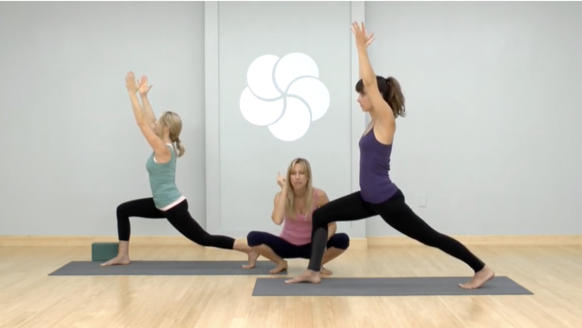 Mulheres a fazerem uma pose numa aula de ioga. 