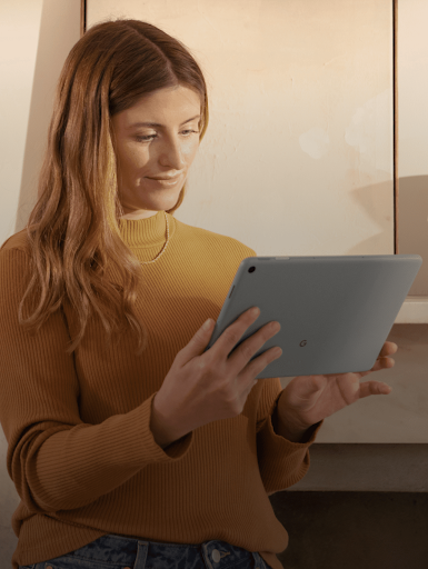 Une femme sourit en regardant l'écran de sa tablette.