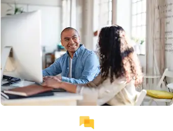 Duas pessoas a trabalhar próximas uma da outra em frente a um monitor de grandes dimensões.