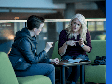 Two women have a conversation using sign language discussing a magazine article.