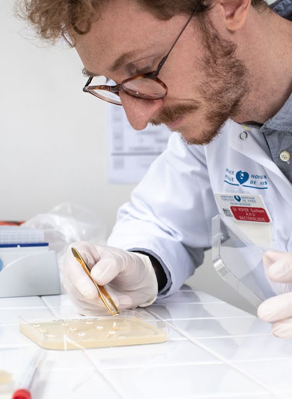 Man in science lab wearing lab coat and working with samples.