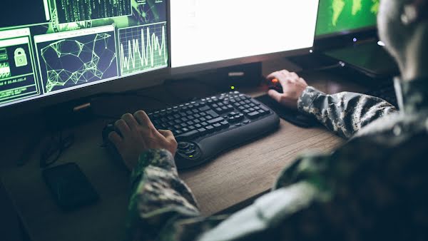 American soldier in fatigues working on a computer in a control center