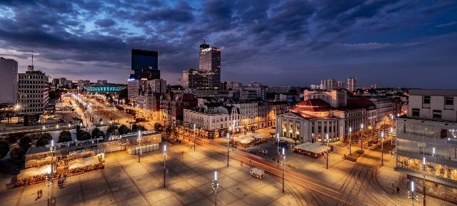 An aerial view of a city at night with lots of lights and buildings.