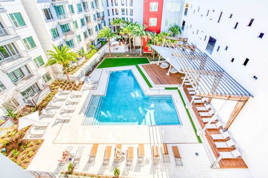 An aerial view of a large swimming pool surrounded by chairs and umbrellas.