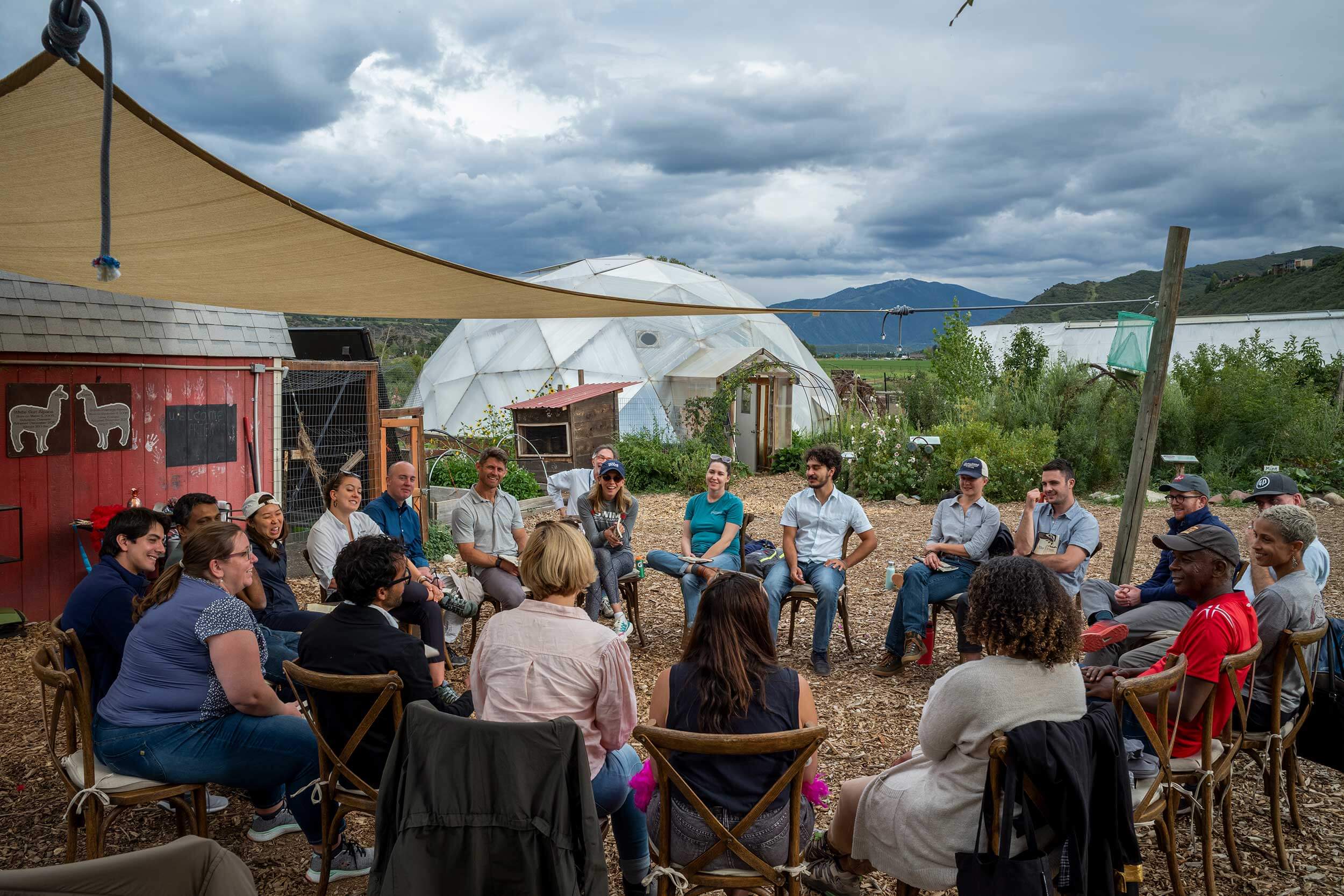 Group of people sitting in a circle on a farm in the mountains