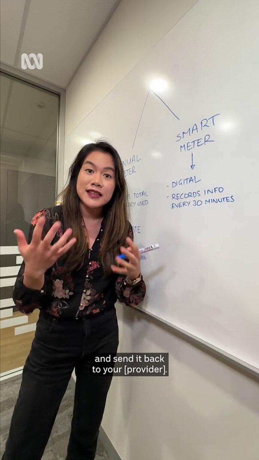 A young woman with dark hair and medium-tone skin stands in front of a whiteboard that includes the words "smart meter" written