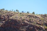 A helicopter unloads SES volunteers onto a clifftop near Lake Argyle.