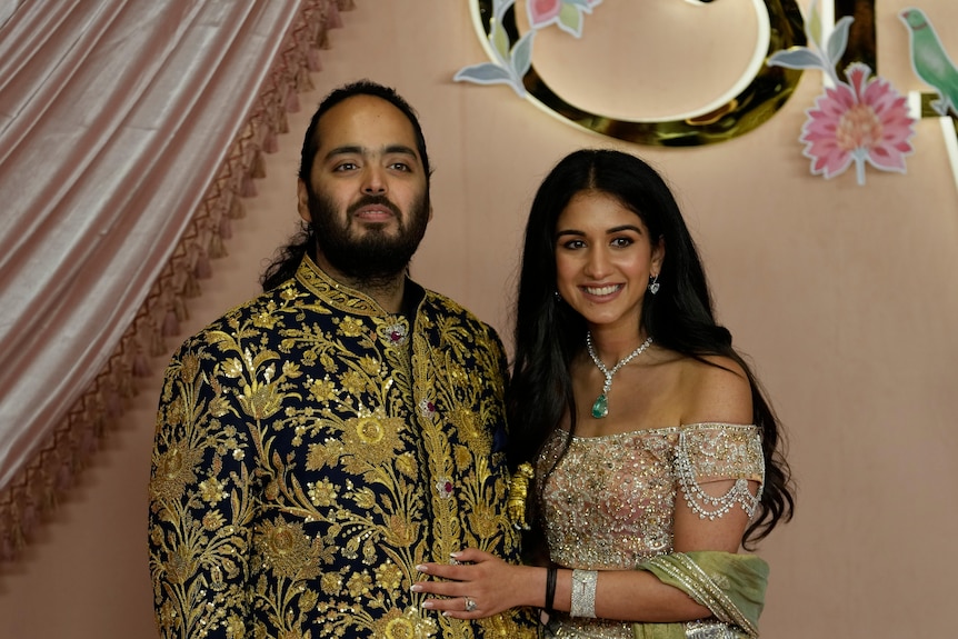 Anant Ambani and Radhika Merchant smile while wearing lavish outfits.