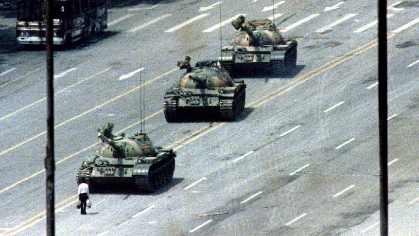 A man stands in front of a row of tanks