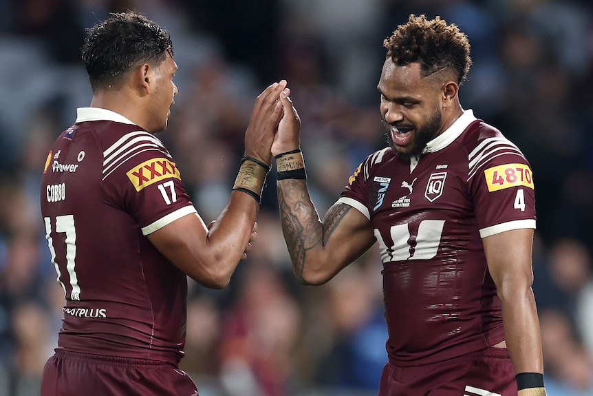 Selwyn Cobbo high-fives Queensland Maroons teammate Hamiso Tabuai-Fidow during State of Origin I.