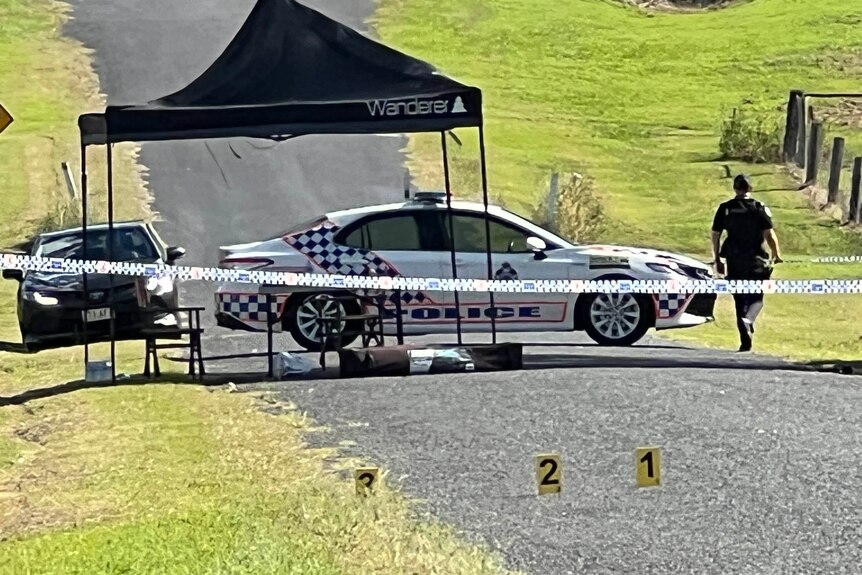 A police officer and vehicle at a crime scene.