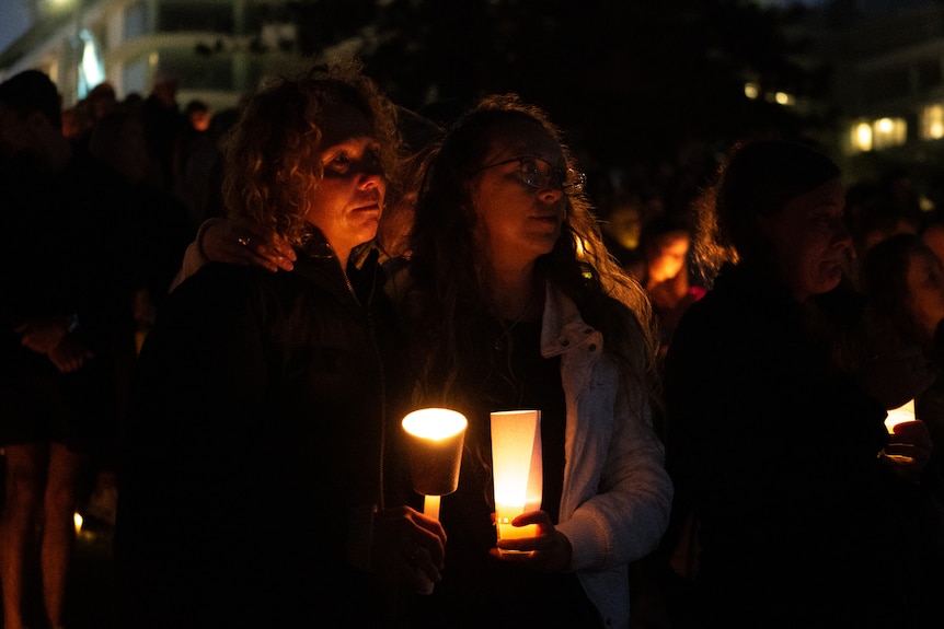 Two women watch with candles in the hands.