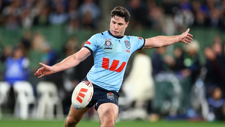 A man kicks a ball during a State of Origin match