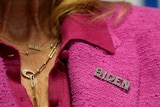 Jill Biden wears a pink suit with a pin that says BIDEN on the collar.