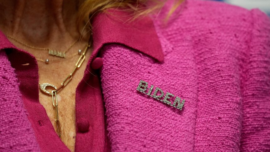 Jill Biden wears a pink suit with a pin that says BIDEN on the collar.