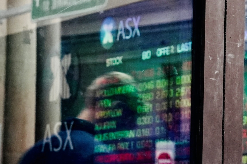 A man looks at a share price board outside the ASX in Sydney.