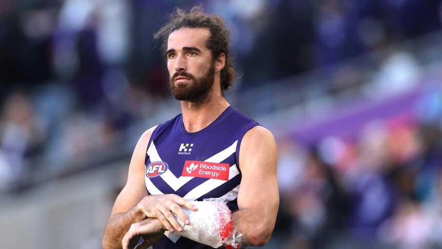 A footballer on the field holding a bandage against his arm