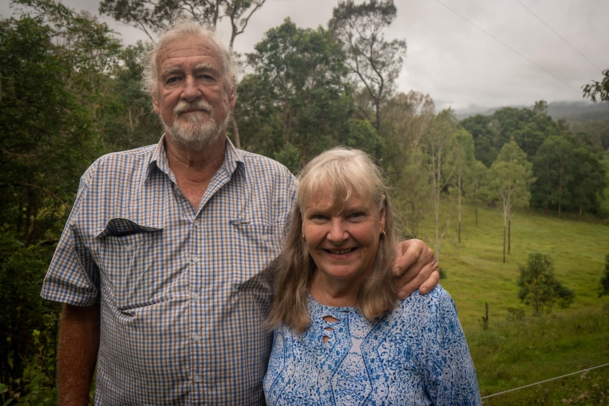 A man and woman standing in front of a green background