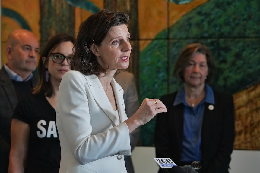 Allegra Spender wearing white in front of mental health advocates