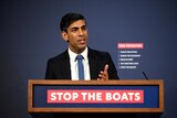 Sunak speaks in front of a lectern emblazoned with the slogan "stop the boats".