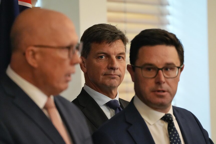 Three men in suits, looking serious.