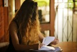 Unidentified woman looks away while holding medical records.