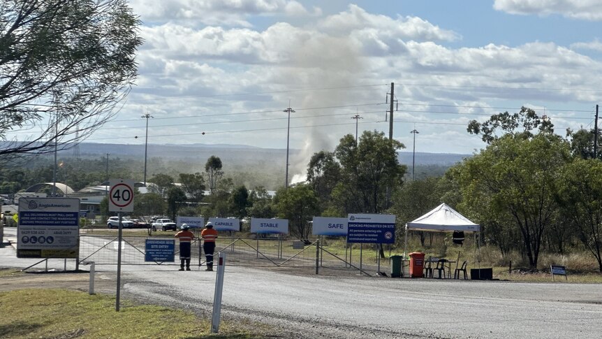 Smoke rises out of the ground in a cordoned-off area of bushland.