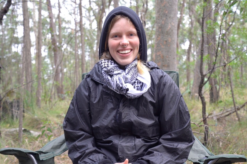 woman sitting on camp chair in forest 