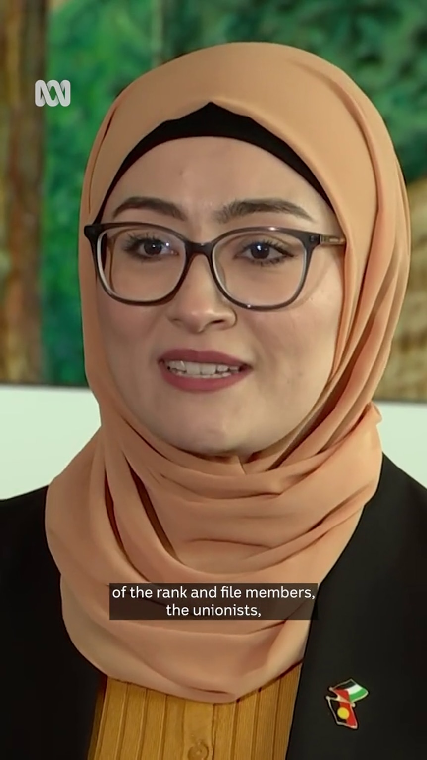 Fatima Payman wears a head scarf with a black jacket adorned with a badge made up of Aboriginal and Palestinian flags