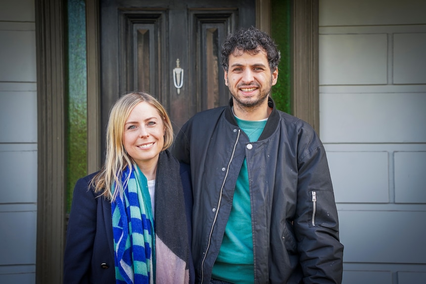 A man and woman standing in front of a house