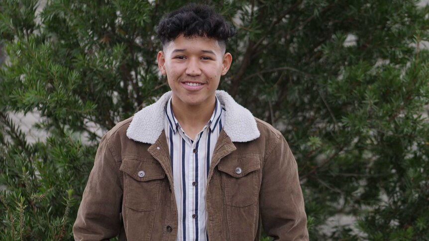 Ali, standing facing the camera in front of a tree.