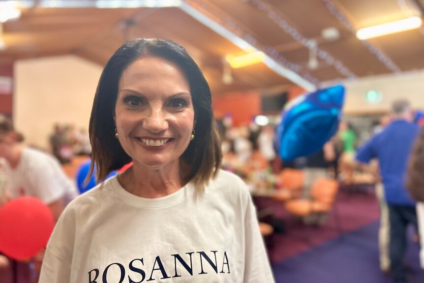 woman smiling wearing t-shirt in building with balloons background