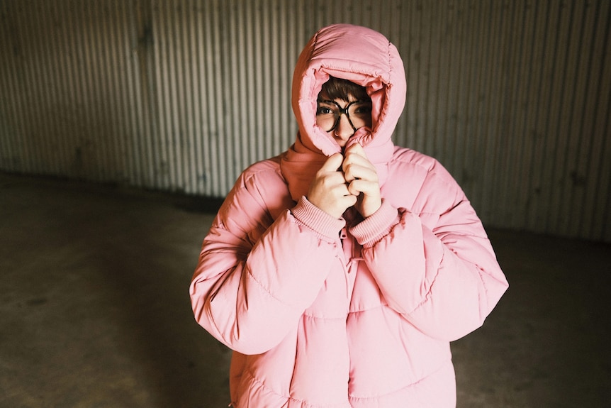 woman wearing a pink puffer jacket and peaking through the hood