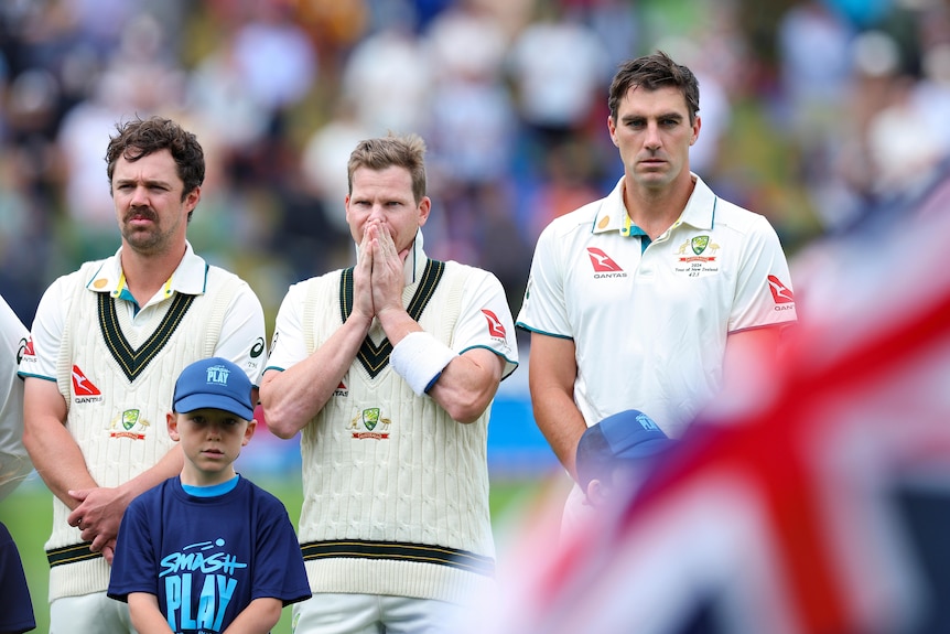 Australian cricketers Travis Head, Steve Smith and Pat Cummins stand for the national anthem before a Test against New Zealand.