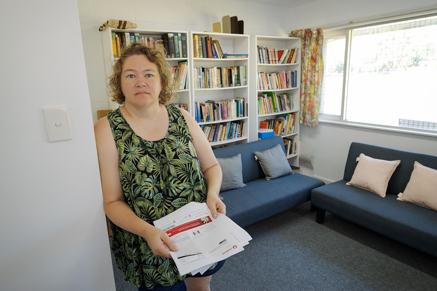 A woman who holds a stack of papers in an office.