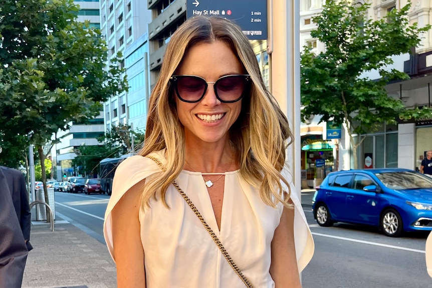 Headshot of a woman in sunglasses walking in a city street