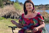 Woman wearing colourful dress sitting beside a river. 