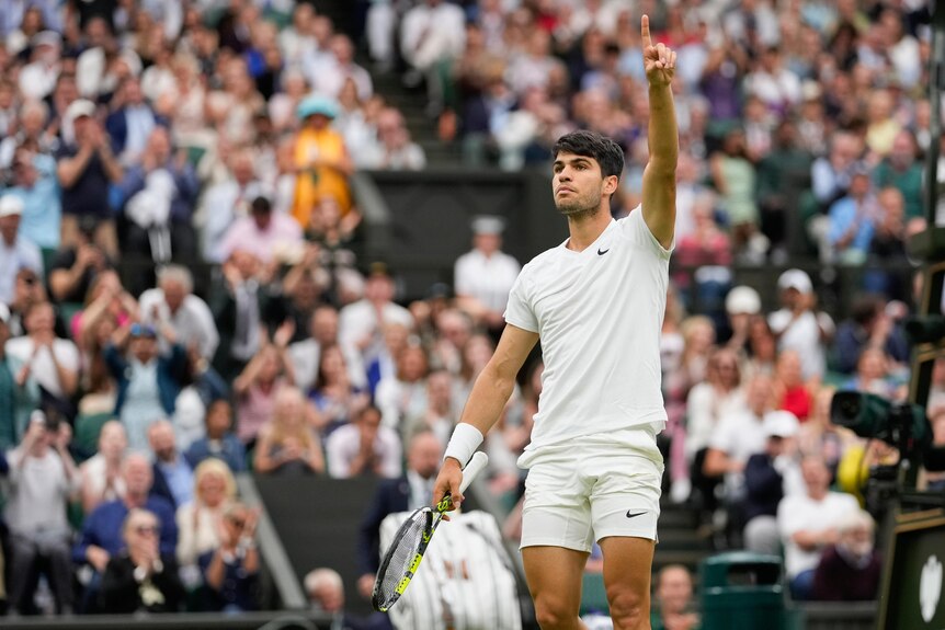 Spanish tennis star Carlos Alcaraz points his finger to the sky in celebration after winning a set at Wimbledon.