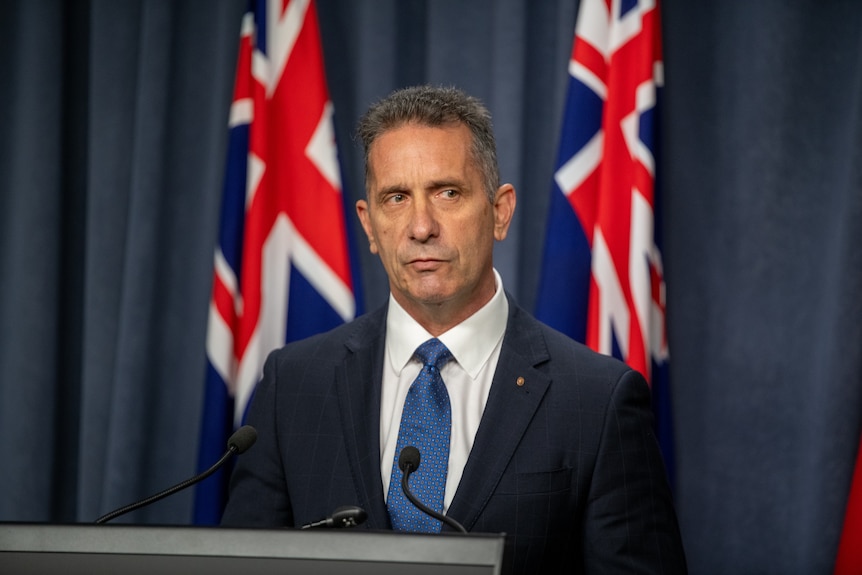 A man stands in front of Australian flags