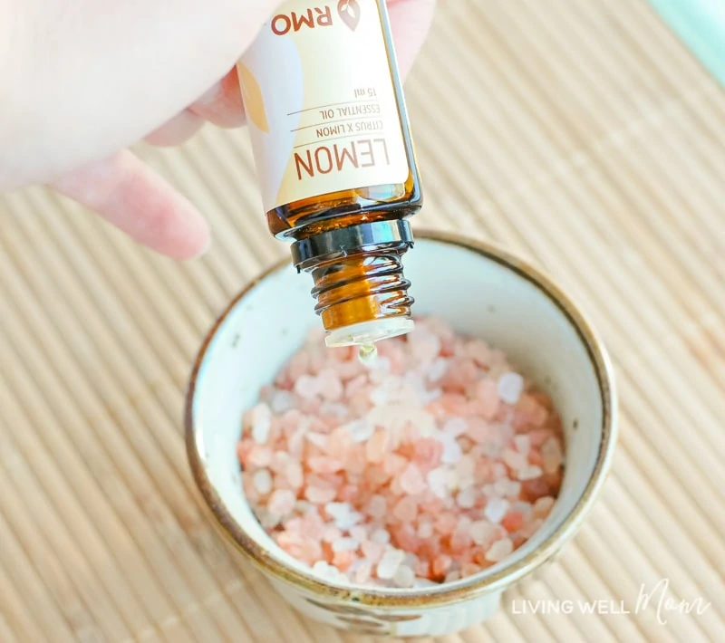 lemon oil being dropped onto of a small bowl of pink rock salt