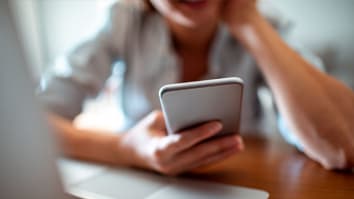 woman looking at smartphone at kitchen table