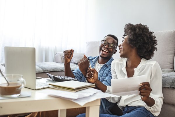 Two adults sitting on floor in front of coffee table are celebrating.